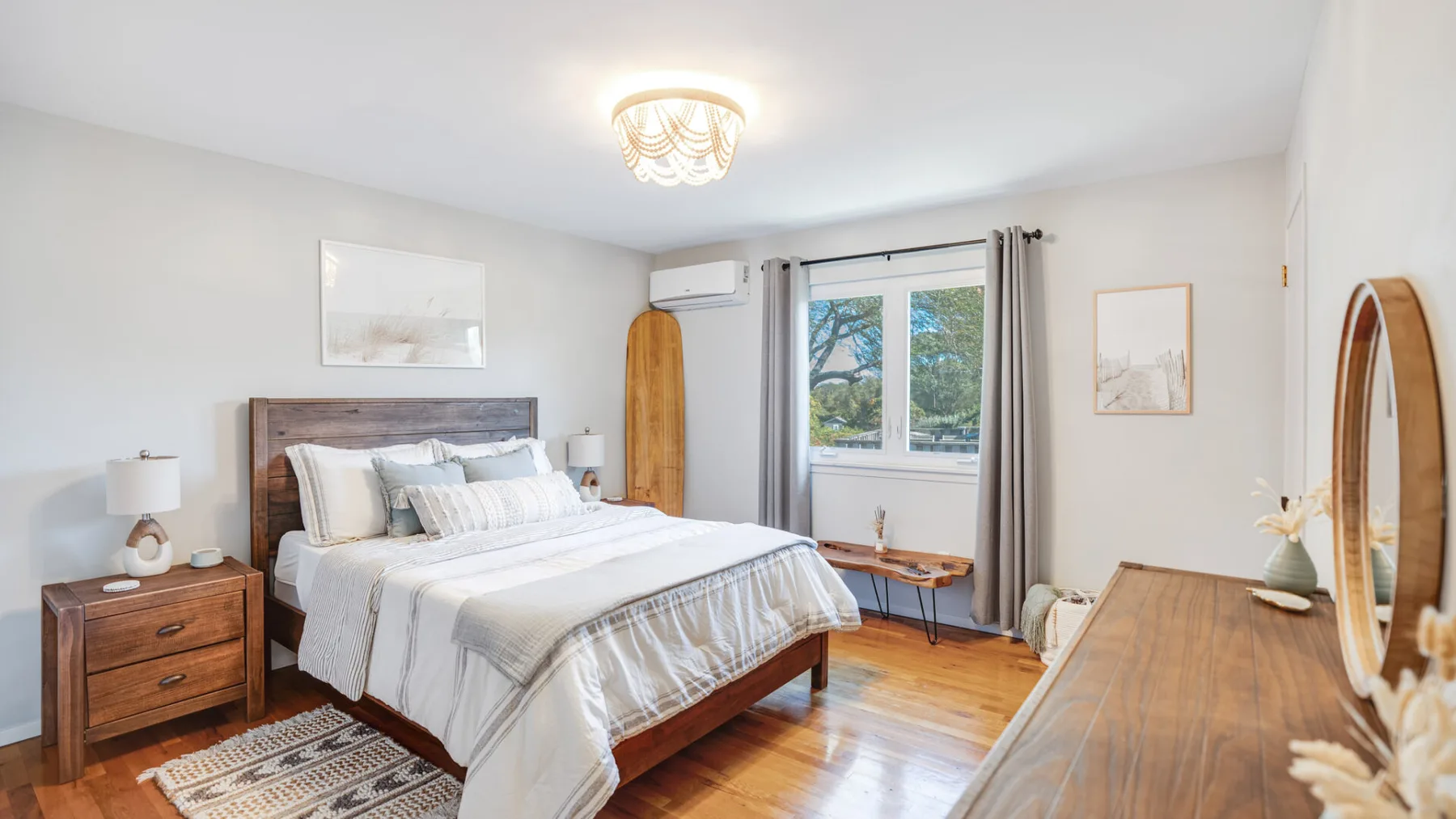 A bright bedroom with a bed beside a window and wooden furnishings.