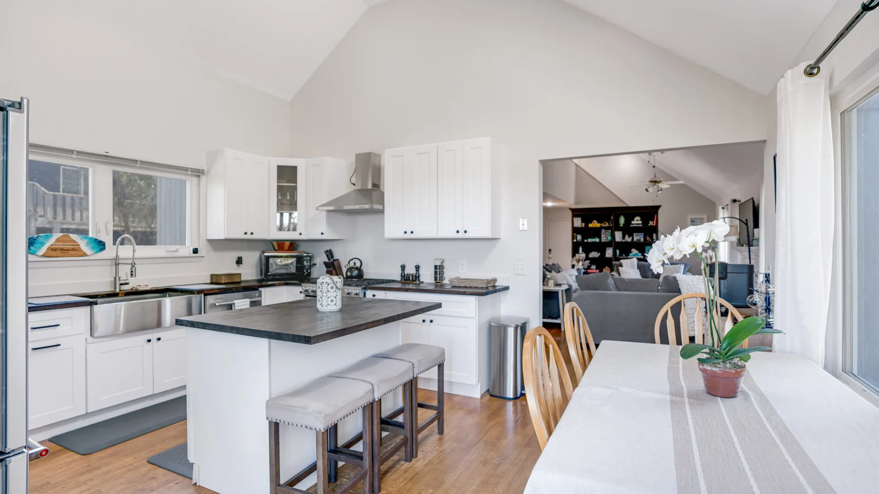 A bright kitchen with a central island opens into a living area.