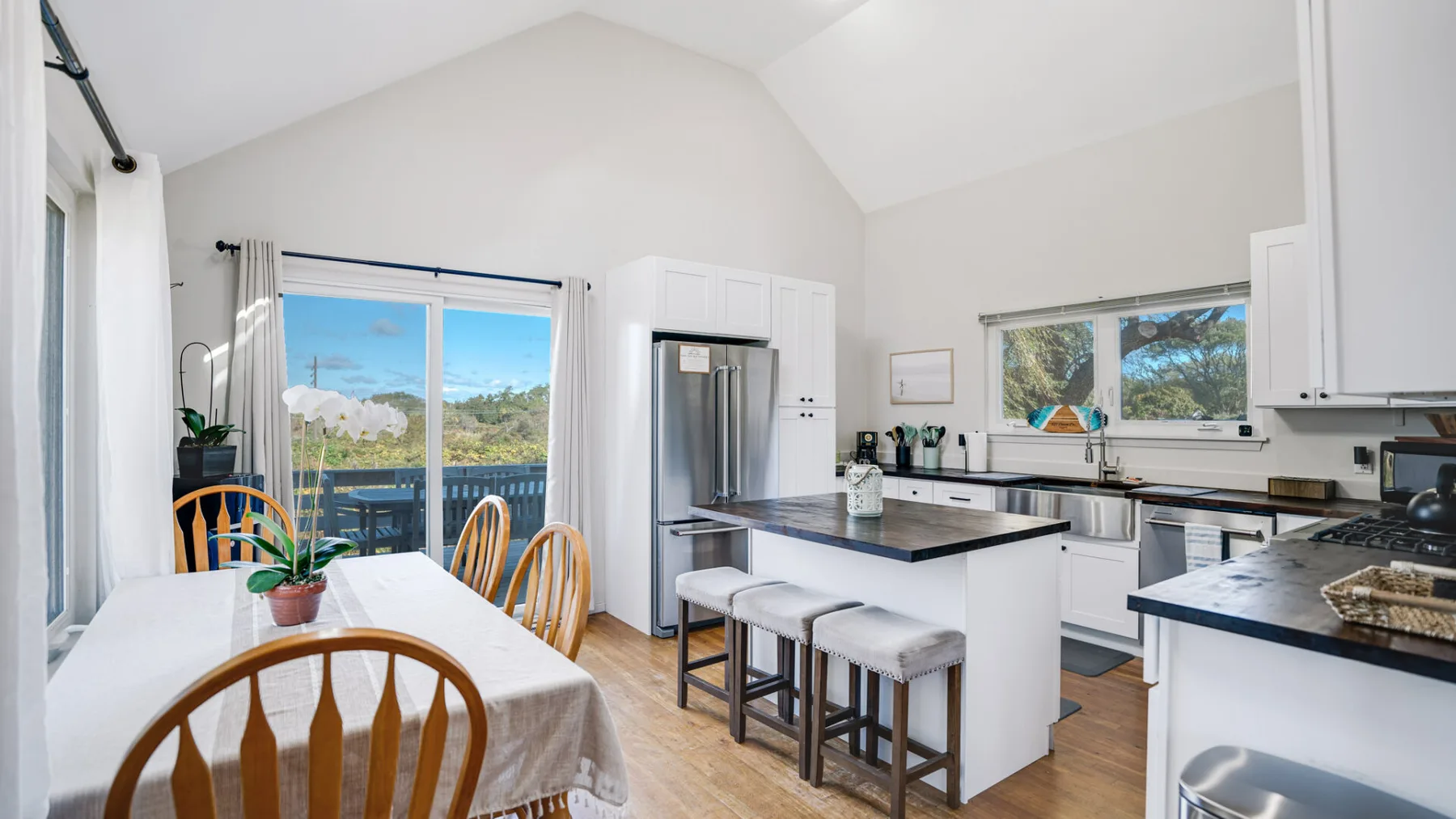A bright open kitchen and dining area with a central island and table by the windows.