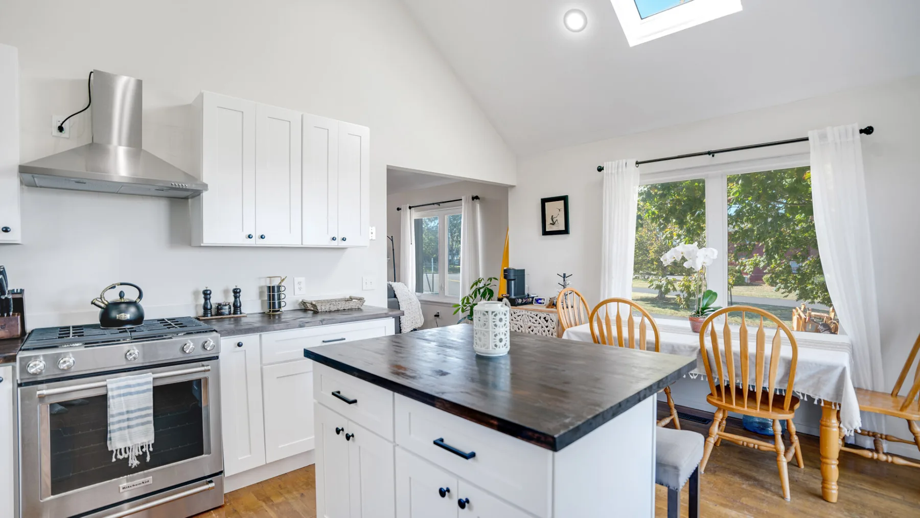 A bright kitchen and dining area with a central island and large windows.