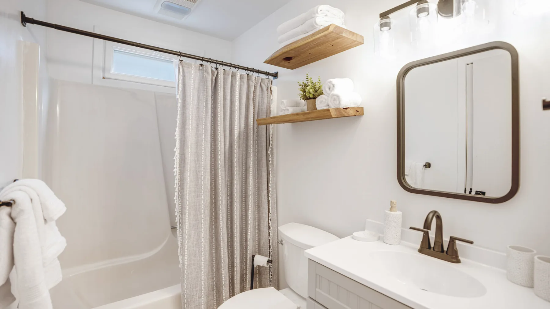 A bright bathroom with a bathtub, shower curtain, and sink vanity.