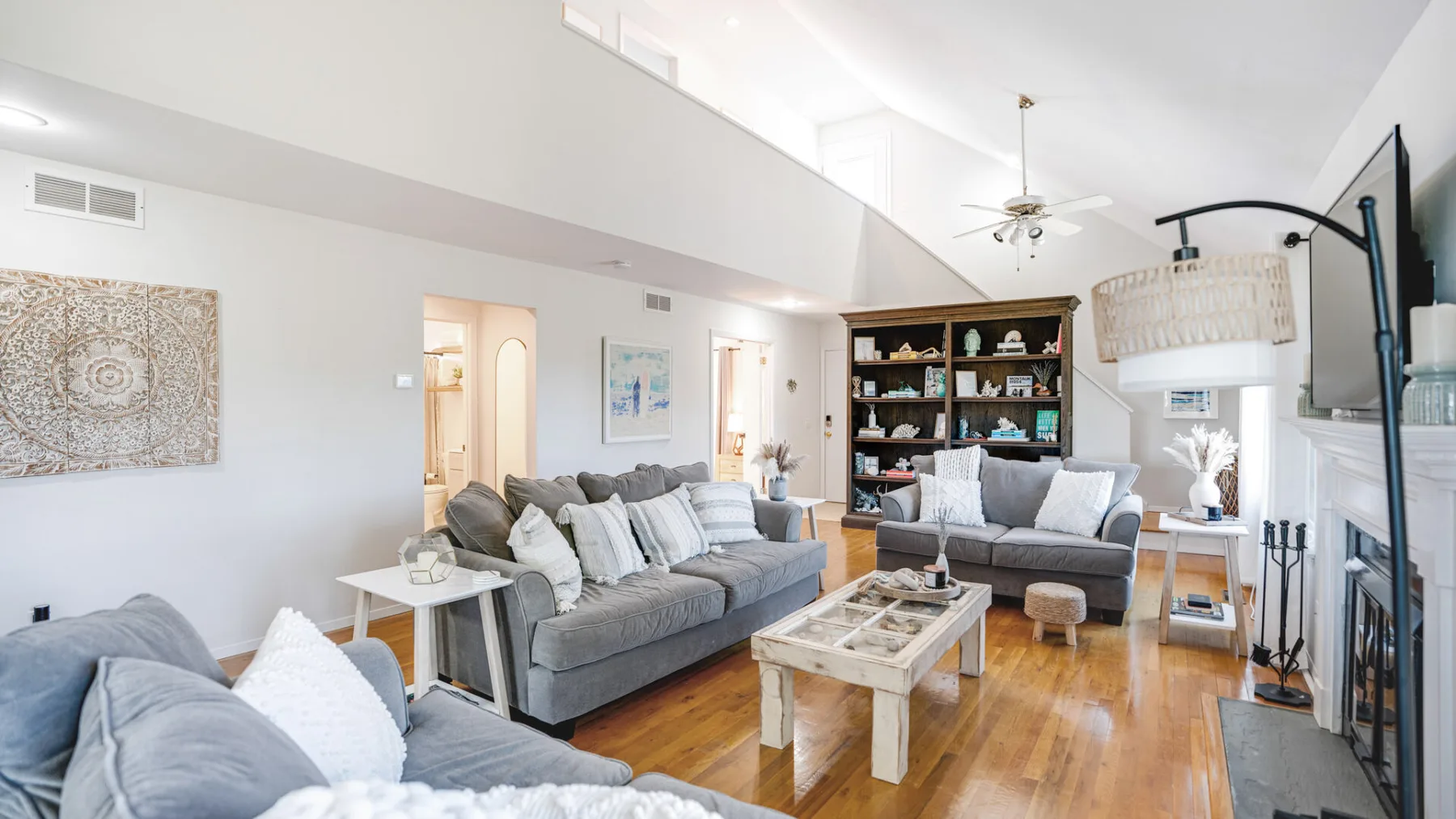 A bright living room with seating arranged around a coffee table and bookshelves.