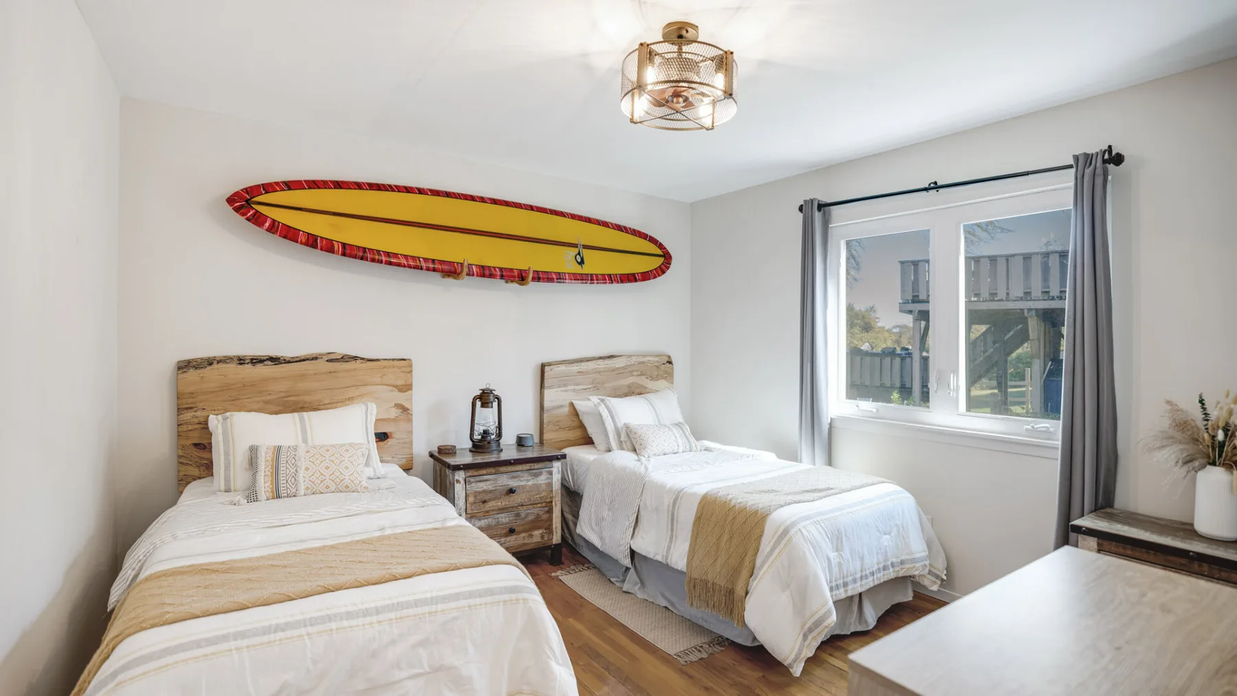A bright bedroom with two beds and a large window.