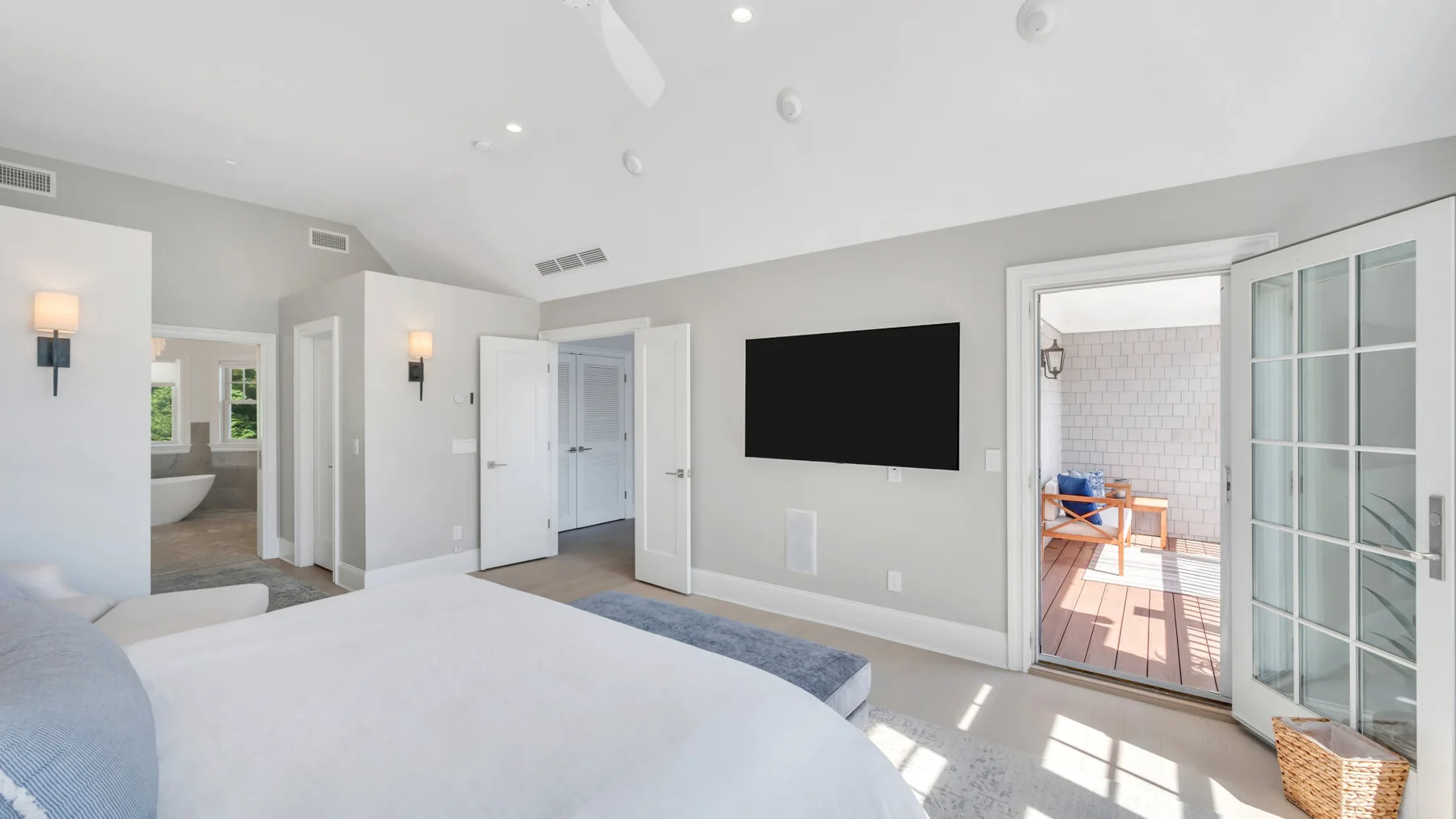 A bright bedroom with a large bed and an open doorway to a balcony.