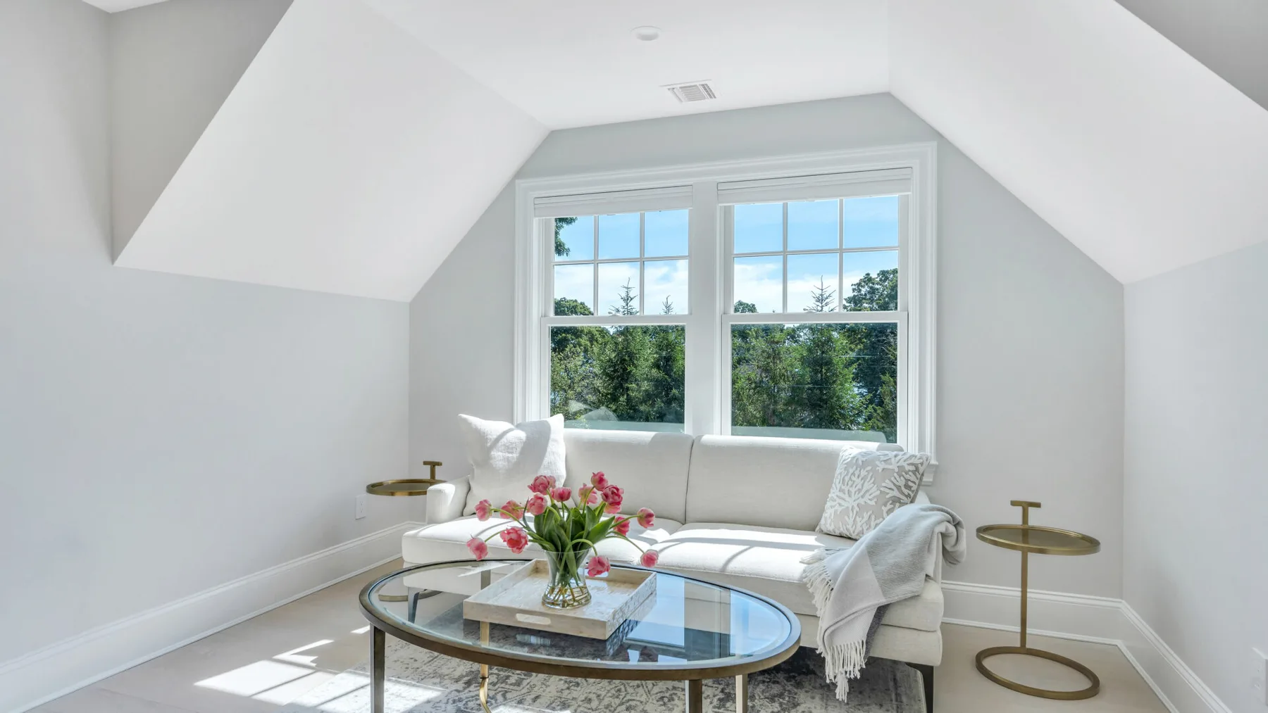 A bright sitting area with a white sofa beneath a large window.