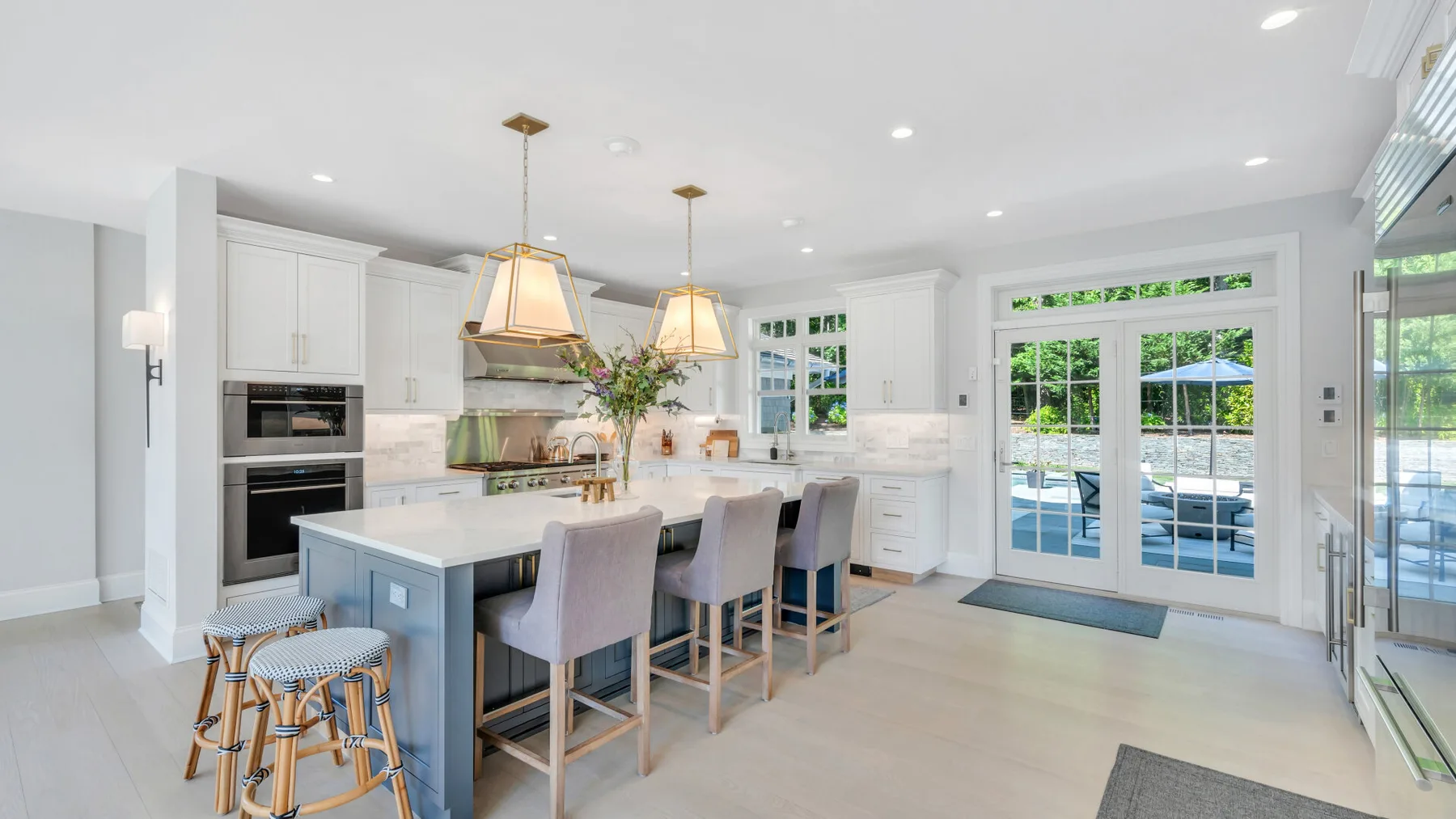 A bright kitchen with an island, bar seating, and glass doors opening to a patio.