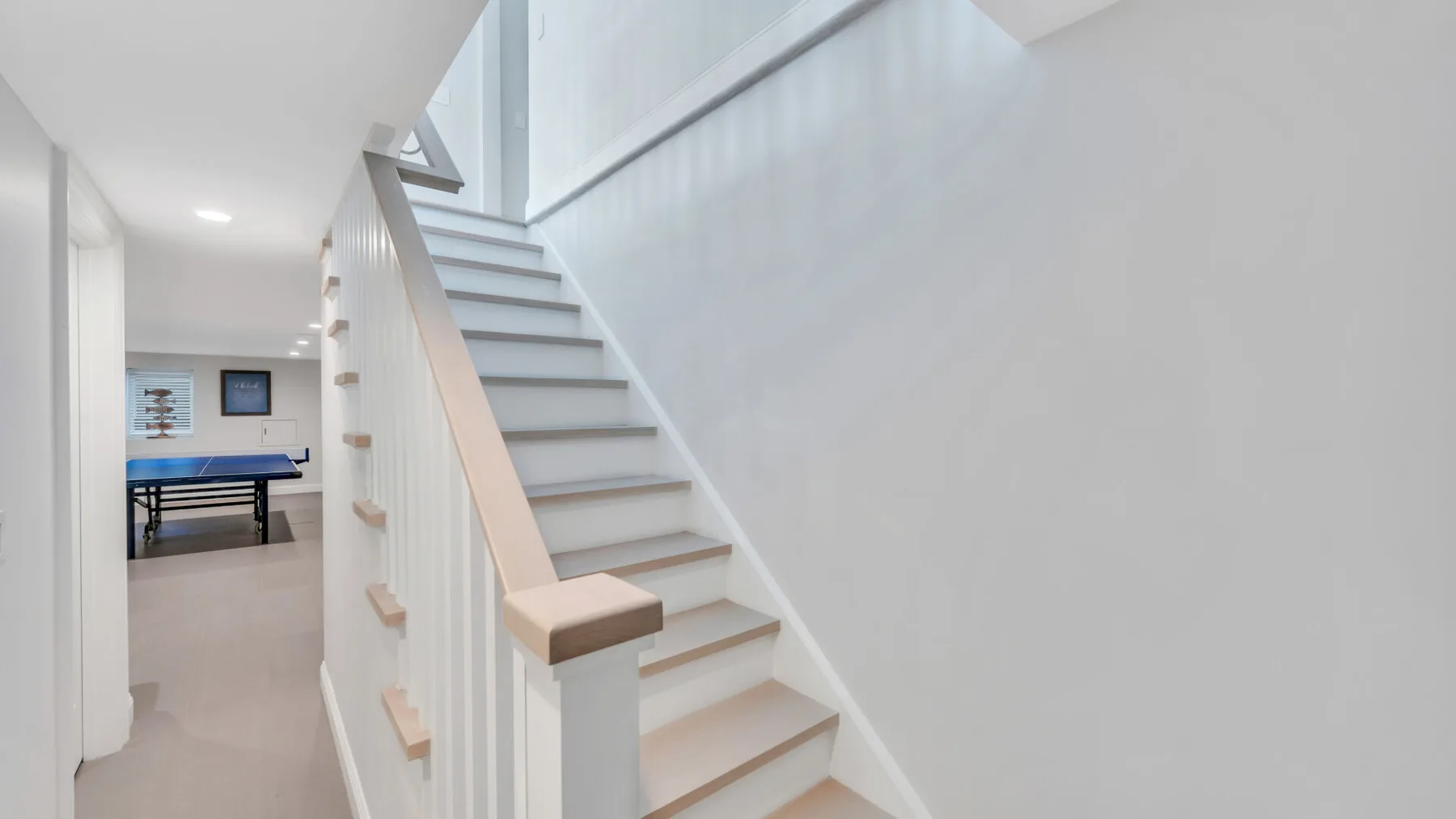 A bright interior hallway features a staircase beside a dining area.
