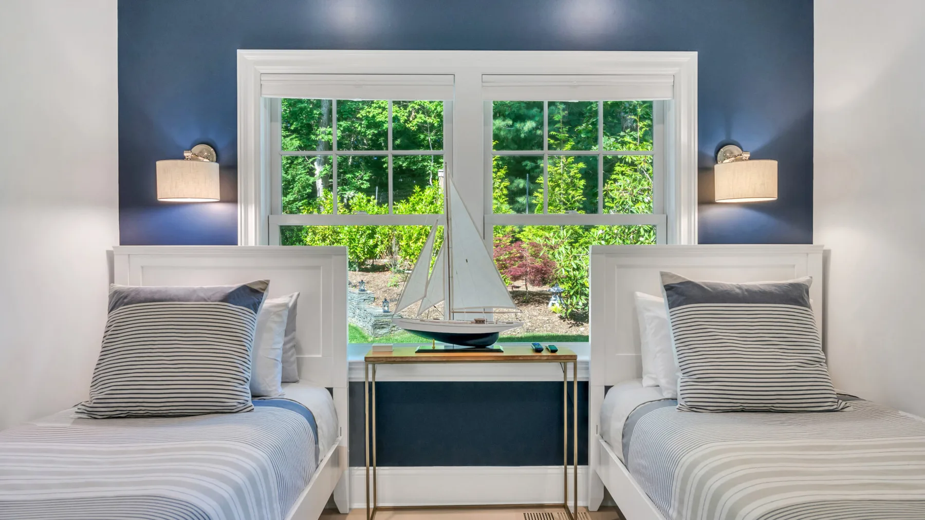 A bedroom with two single beds beside a large window.