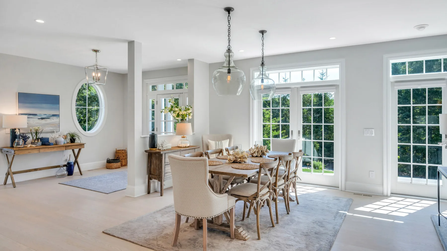 A bright dining area with a wooden table and large windows overlooking greenery.