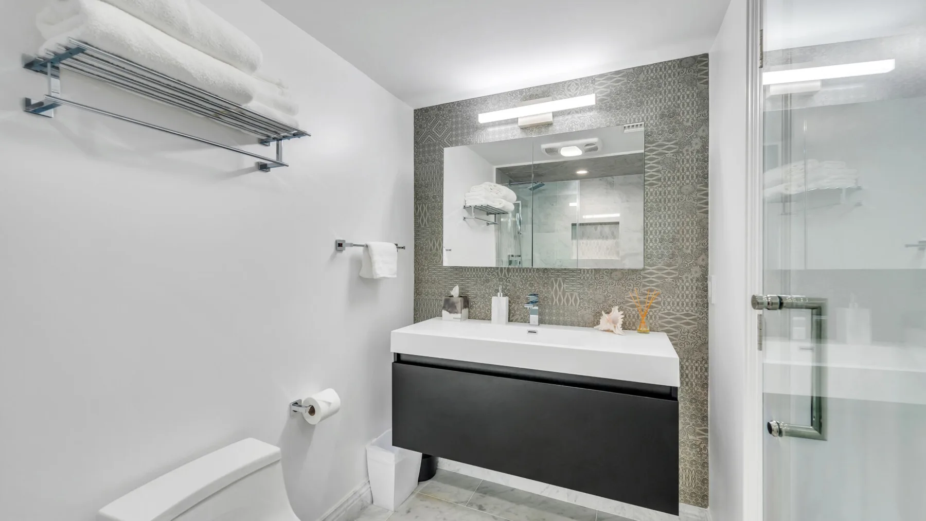 A modern bathroom with a sink vanity, mirror, and glass shower.