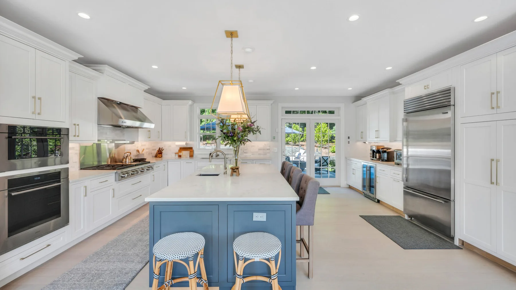 A bright kitchen with white cabinetry and a blue island.