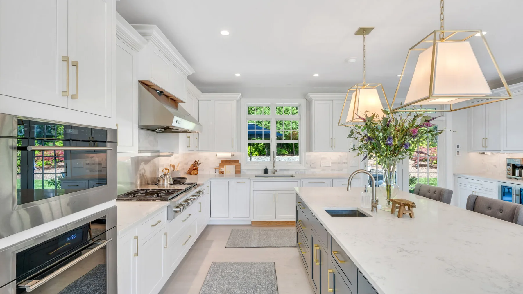 A bright white kitchen with a large island and pendant lights.