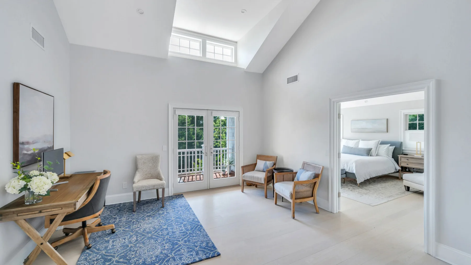 A bright living area with seating beside glass doors and an adjoining bedroom.