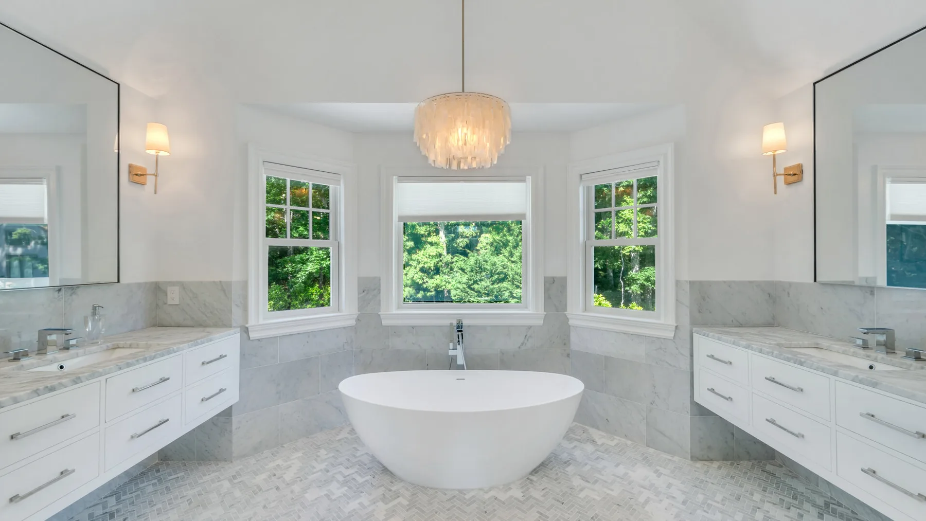 A bright bathroom with a freestanding tub beneath a row of windows.