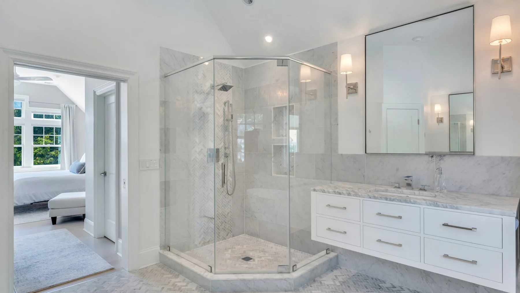 A bright bathroom with a glass shower and a long vanity.