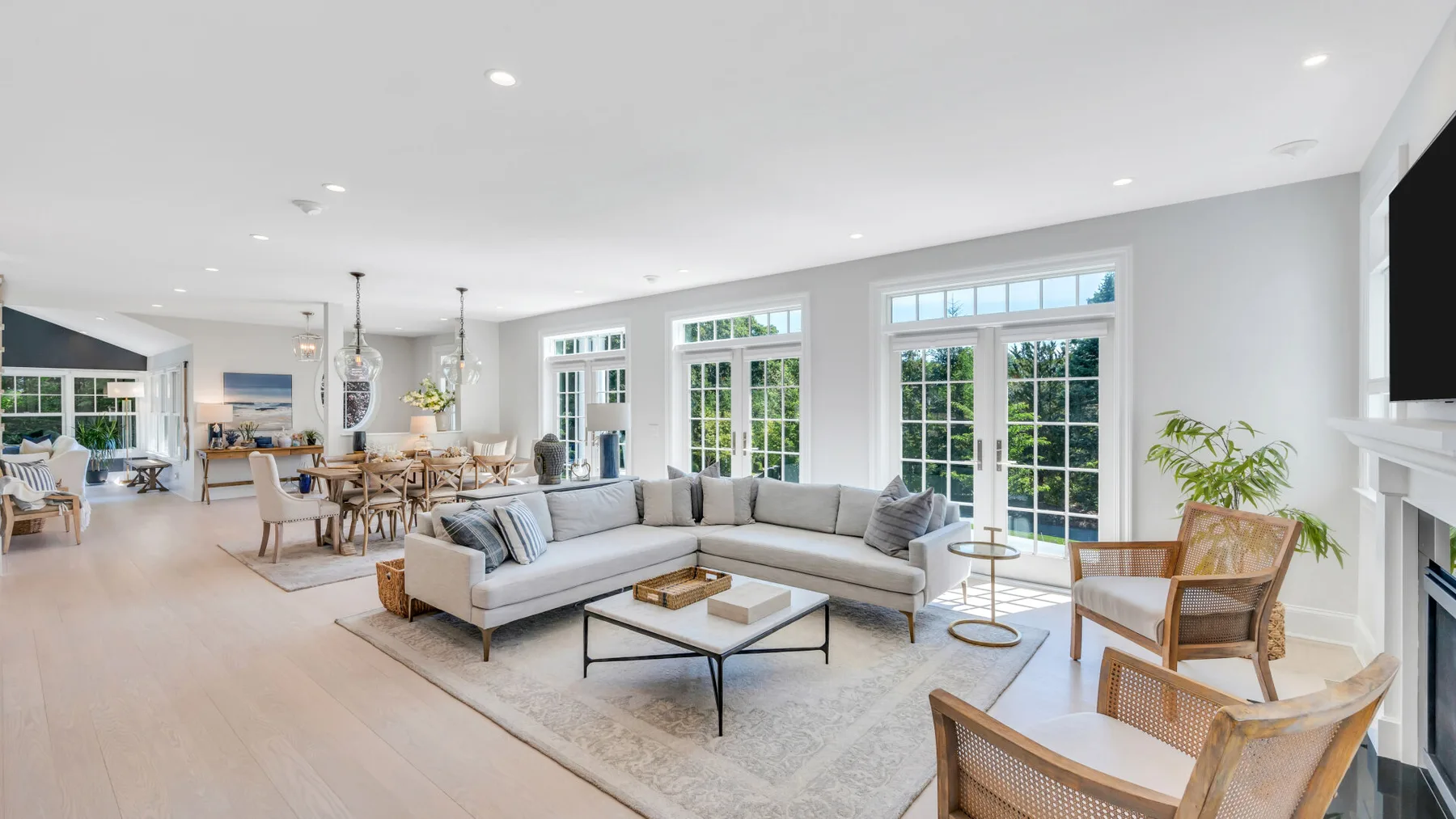 A bright open-plan living room with an L-shaped seating area and large windows.