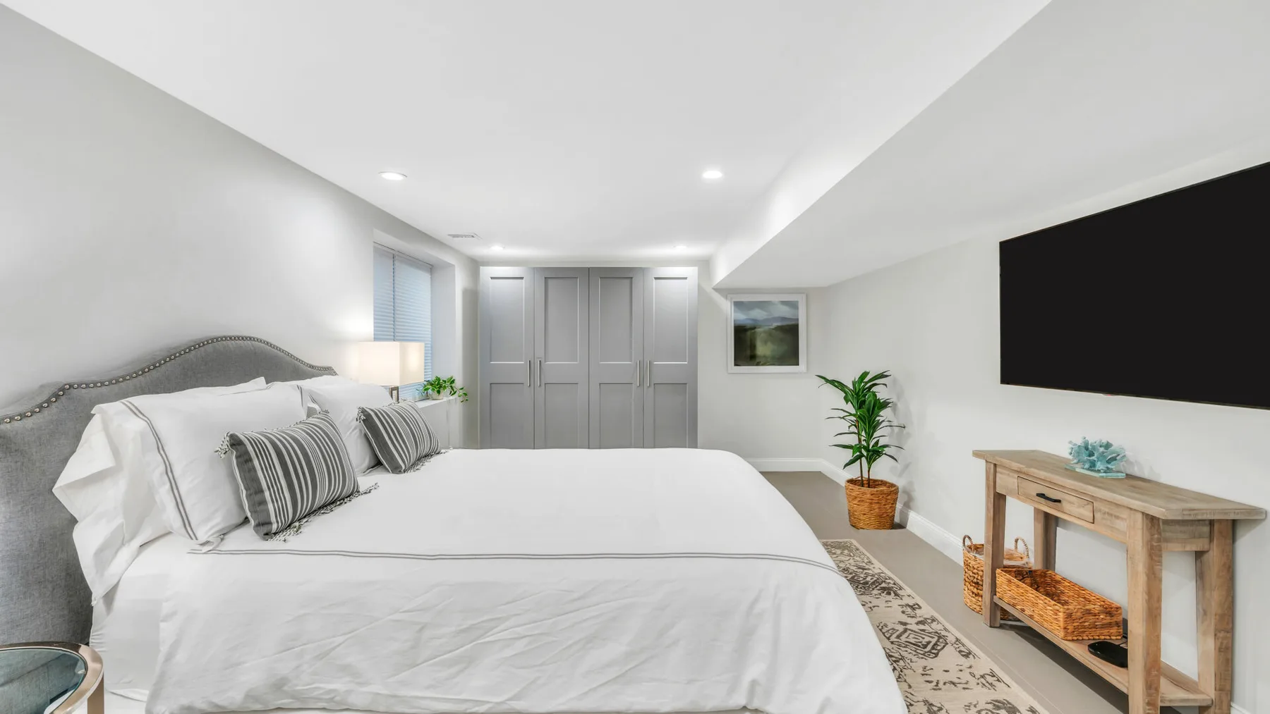 Bedroom with a bed, gray cabinetry, and a large wall-mounted screen.