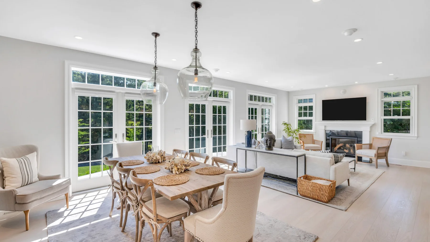 A bright open-plan living and dining room with large windows and seating.