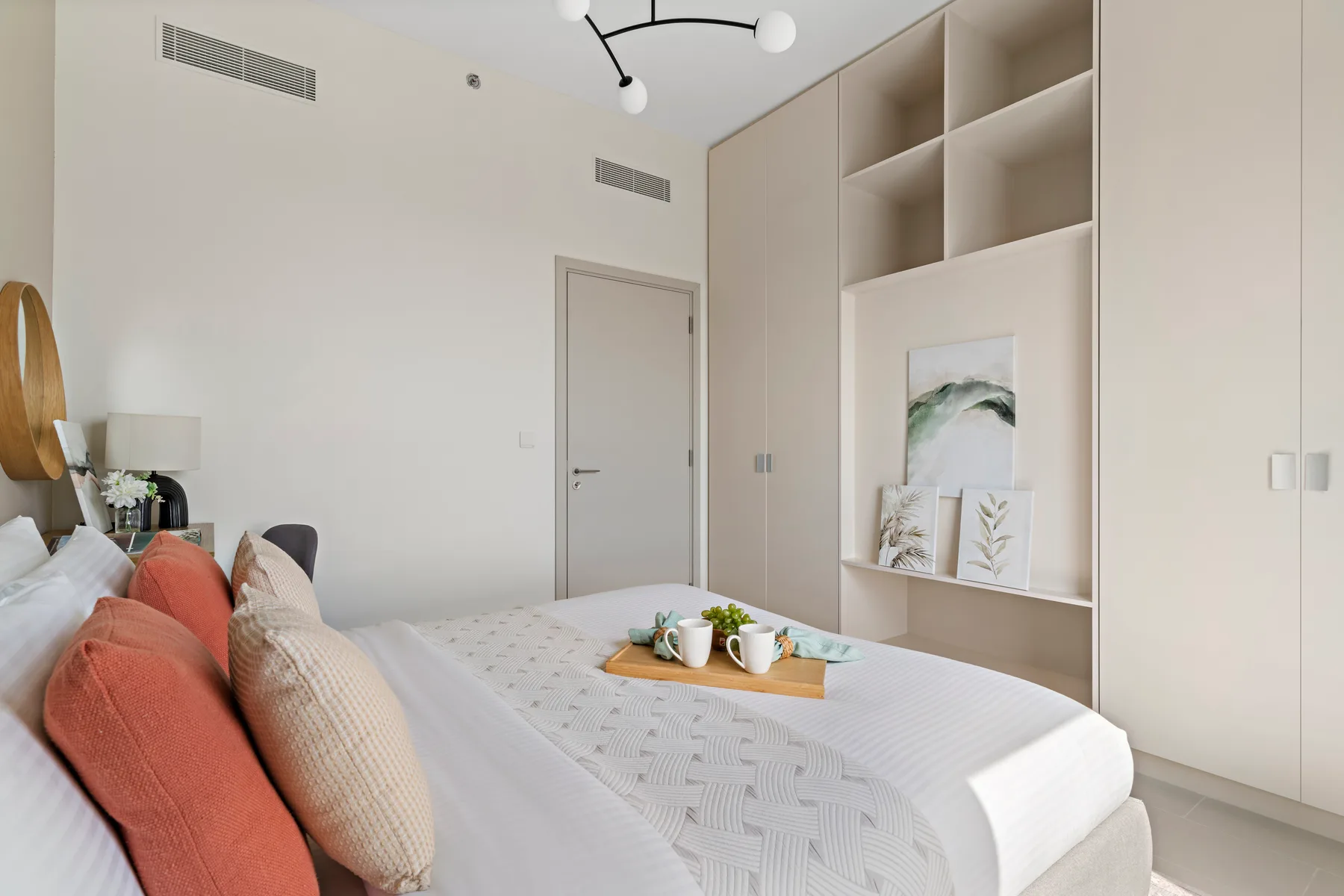 Un dormitorio con una cama bien hecha y estantes empotrados en la pared.
