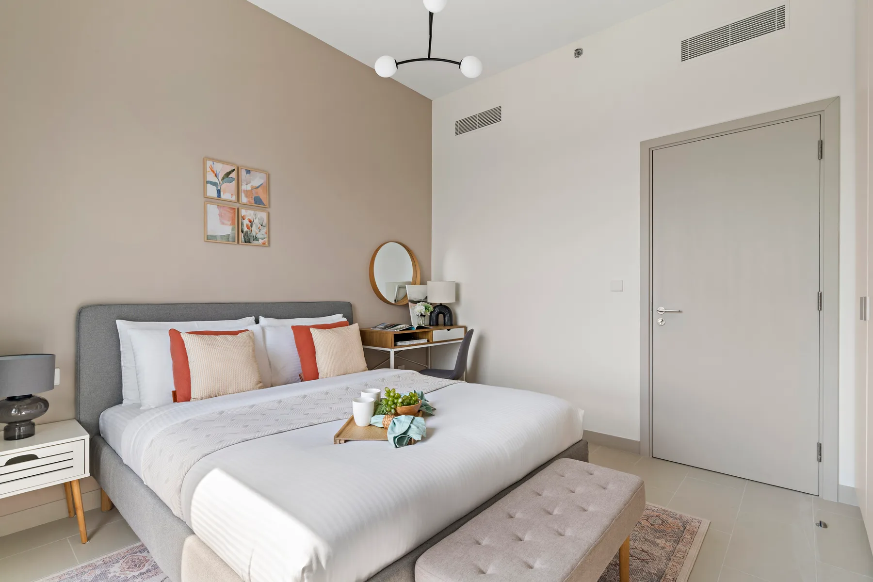 Un dormitorio con una cama bien tendida y un pequeño banco a sus pies.