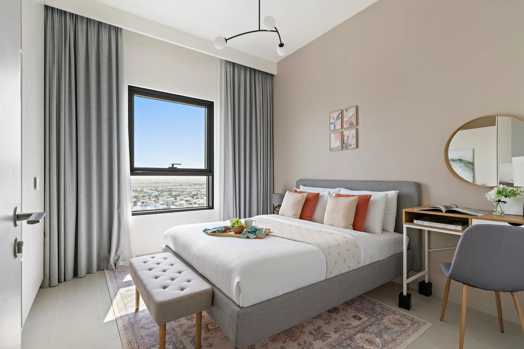 Dormitorio con una cama tendida, cortinas grises y un escritorio junto a la pared.