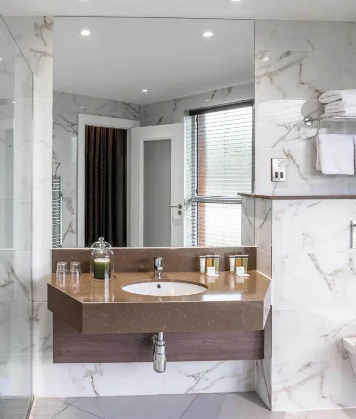 Hotel bathroom with marble tiles and shower.