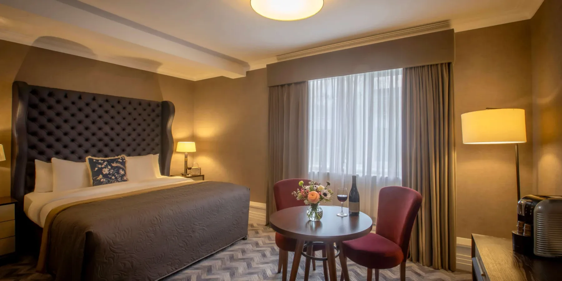Hotel room with a bed and table set for two.
