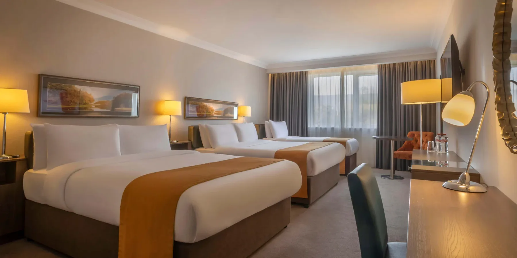Hotel room with three beds and seating.