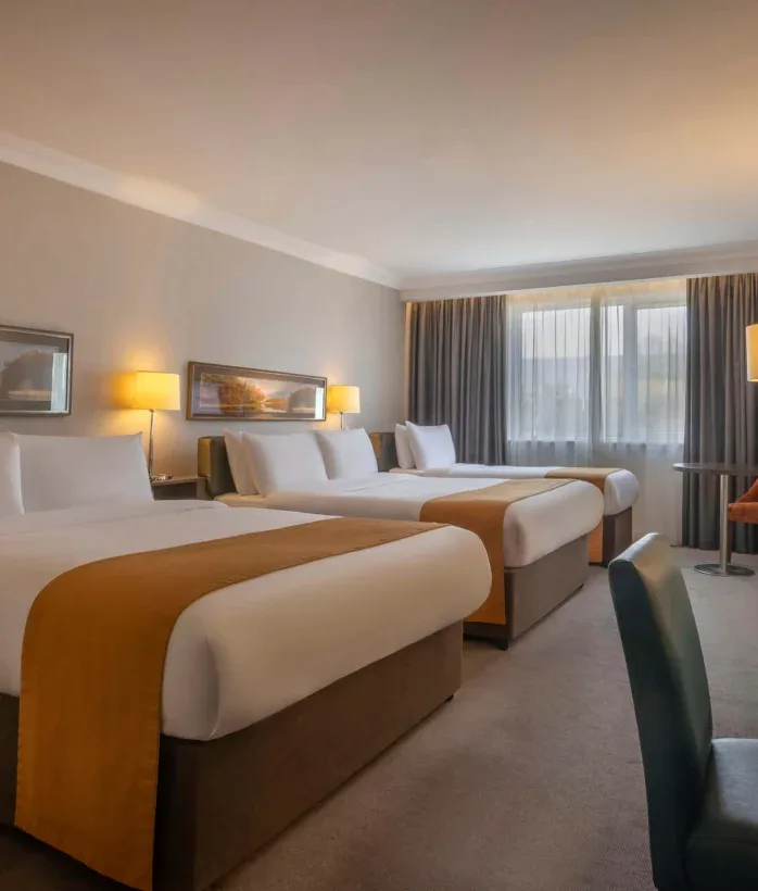 Hotel room with three beds and seating.