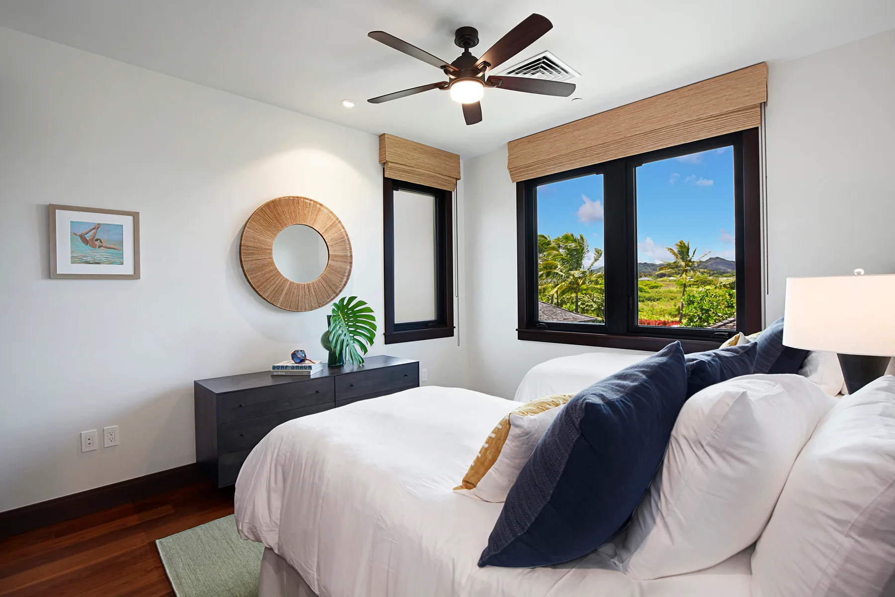 A bedroom with a neatly made bed and large windows overlooking greenery.
