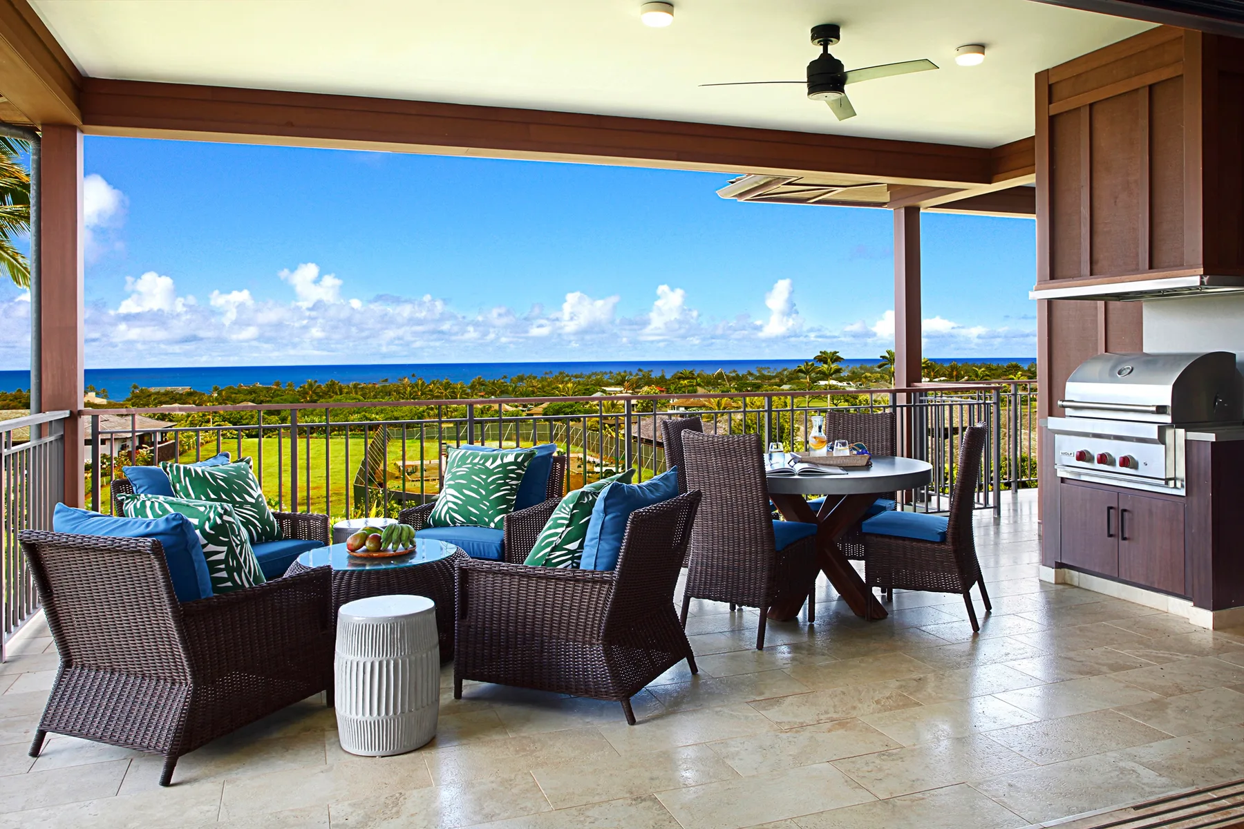A covered outdoor patio has seating and a dining table overlooking the ocean.