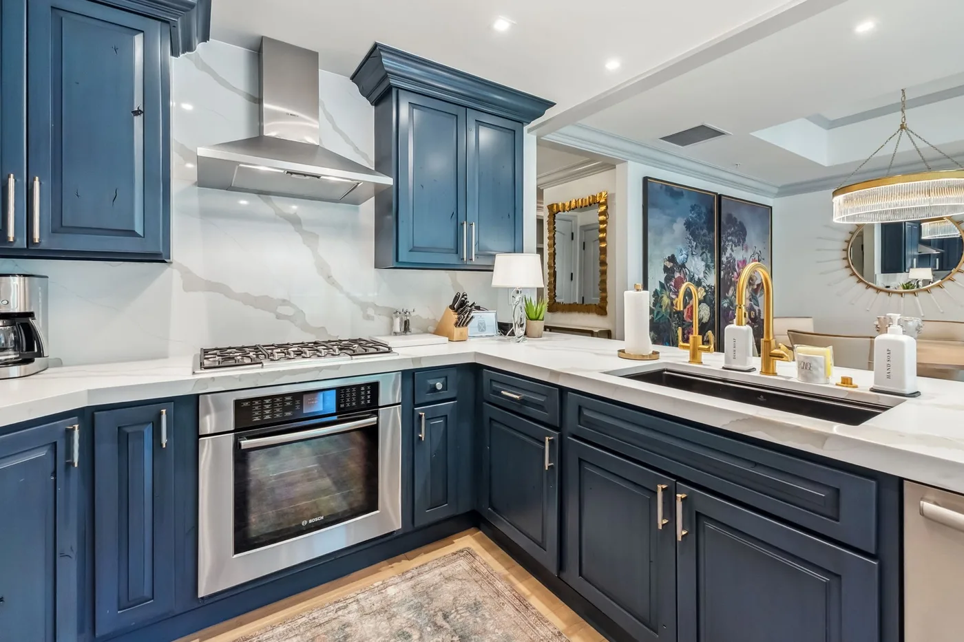 Una cocina con gabinetes azul oscuro, encimeras blancas y una estufa de acero inoxidable.