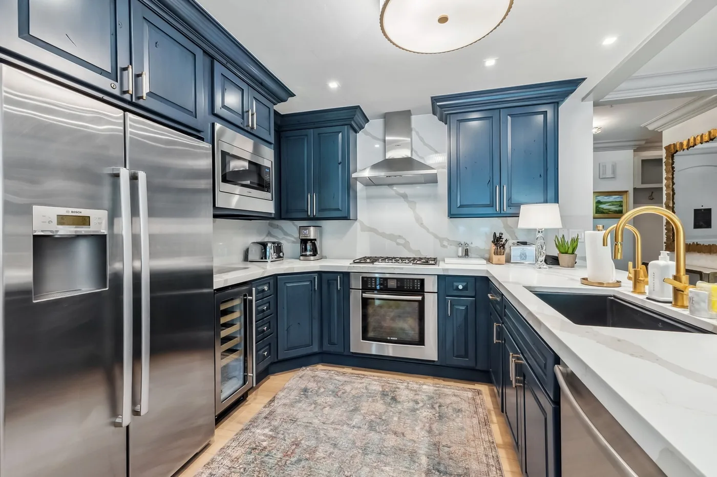 Una cocina moderna con gabinetes azules, electrodomésticos de acero inoxidable y una encimera blanca.