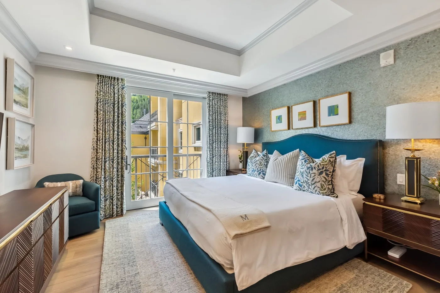 Un dormitorio con una cama bien tendida y puertas de cristal que dan a un balcón.