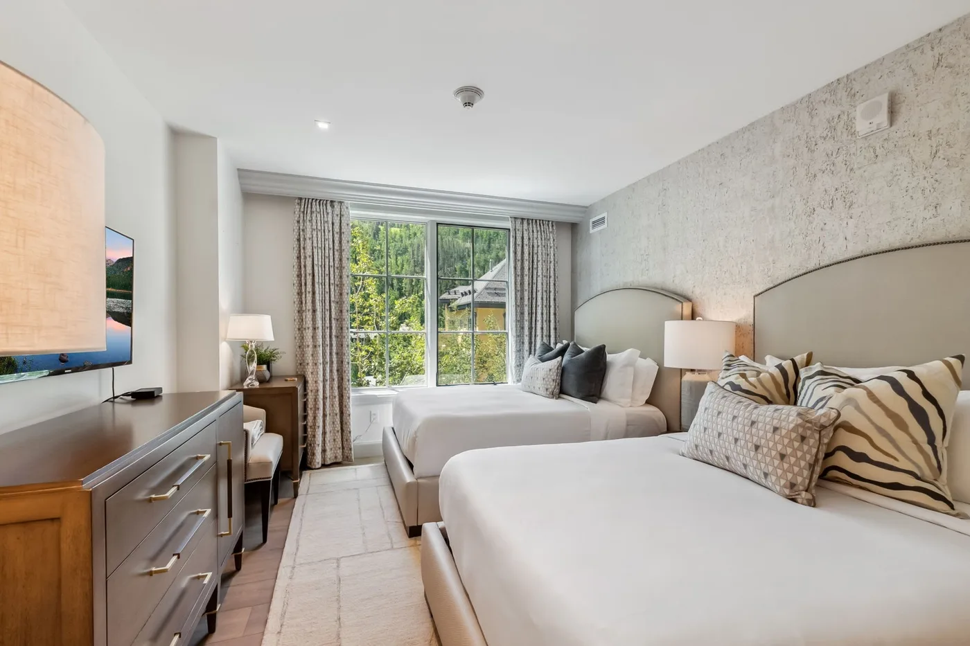 Un dormitorio con dos camas, una ventana y una cómoda.