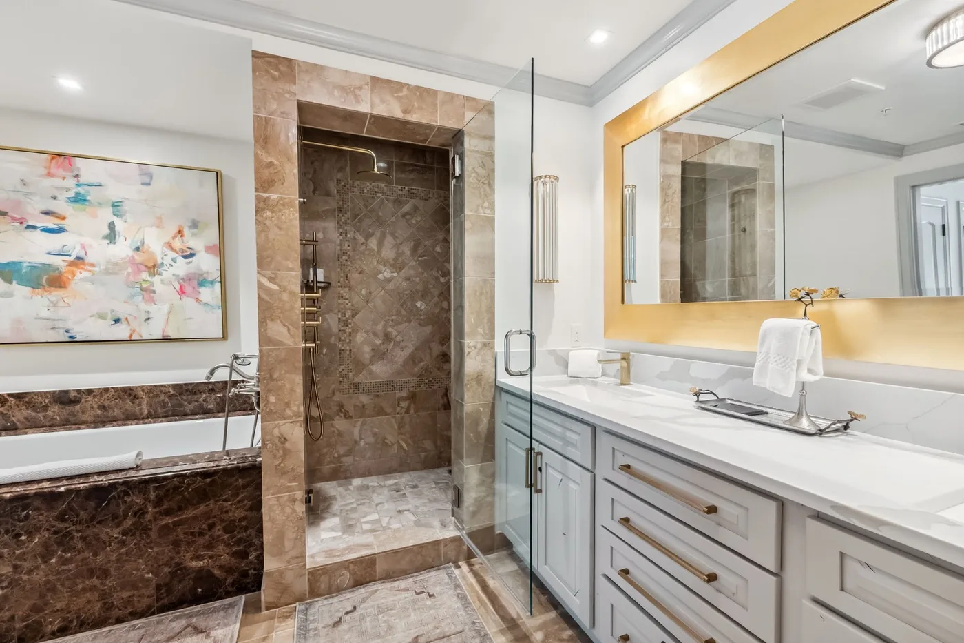 Un baño luminoso con ducha de vidrio, bañera y un largo tocador.