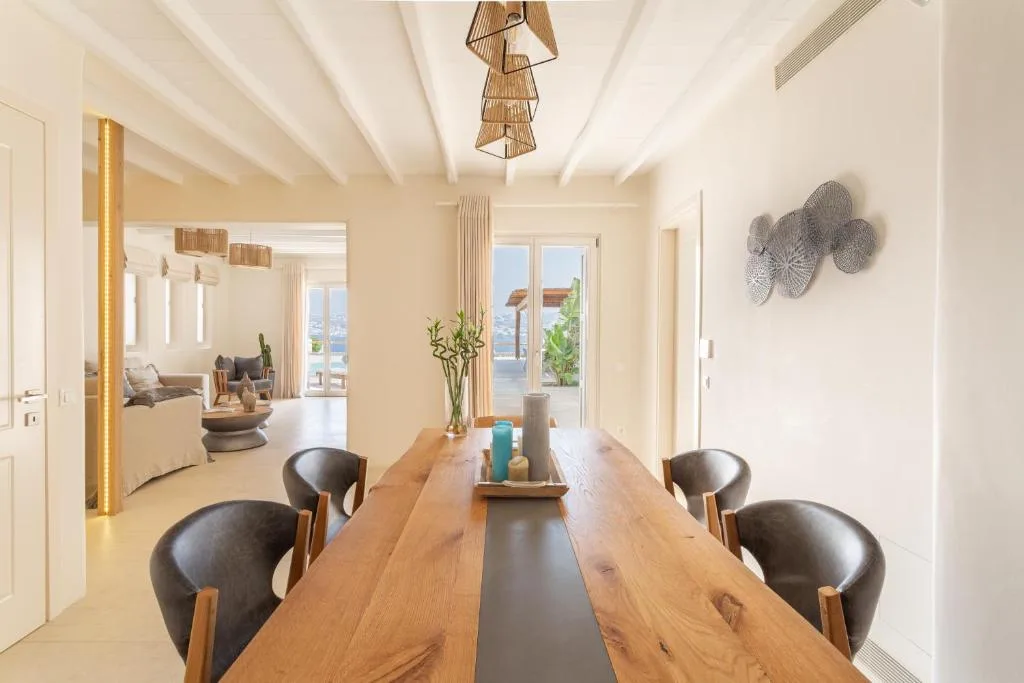 Comedor con una mesa larga de madera y asientos oscuros.