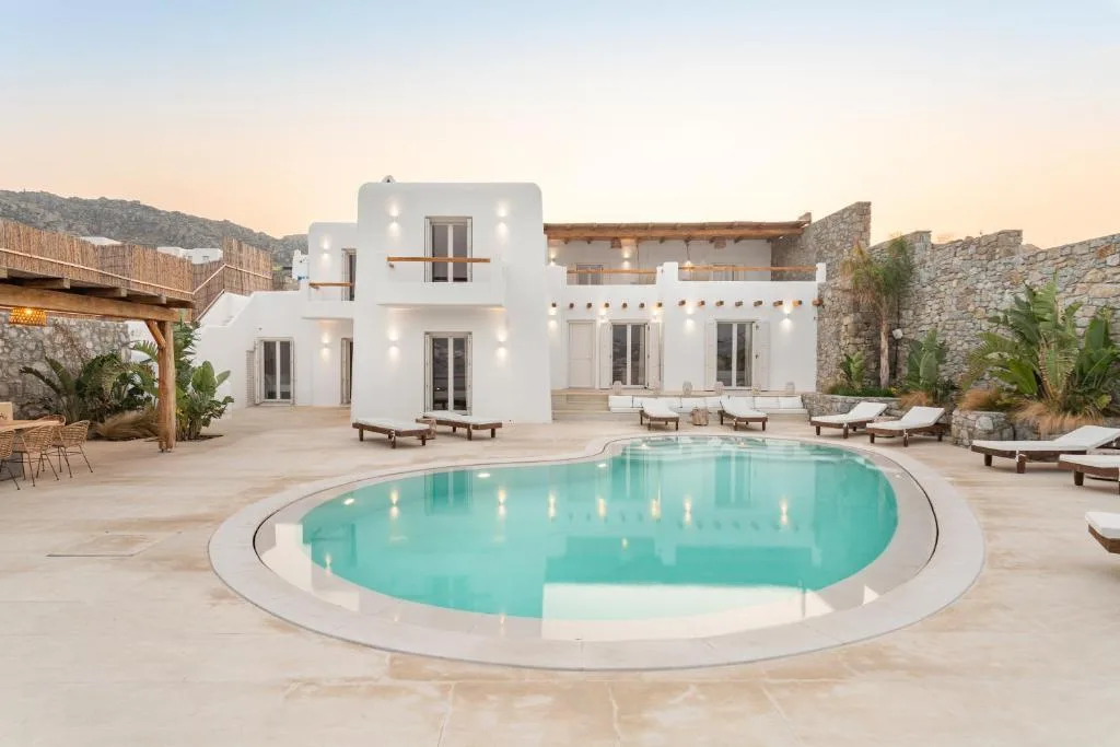 Una villa blanca da a una piscina curva y al patio que la rodea.