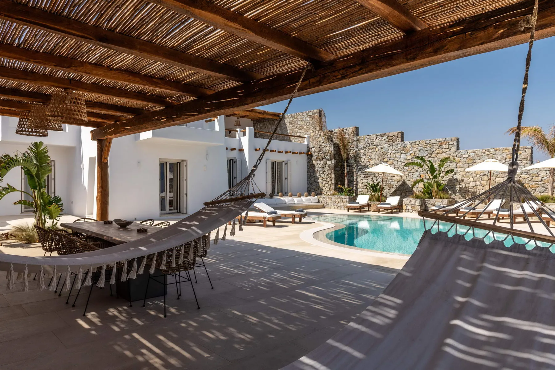 Un patio exterior sombreado da a una piscina, con asientos de descanso cerca.