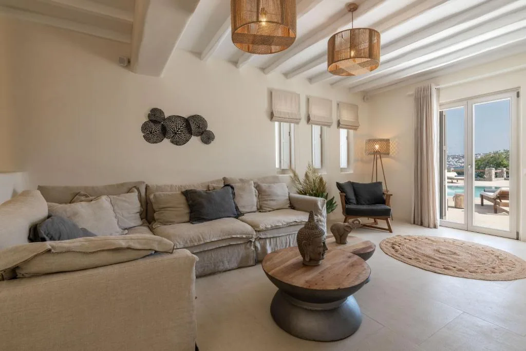 Una sala luminosa con asientos, una mesa de centro redonda y grandes puertas de vidrio.