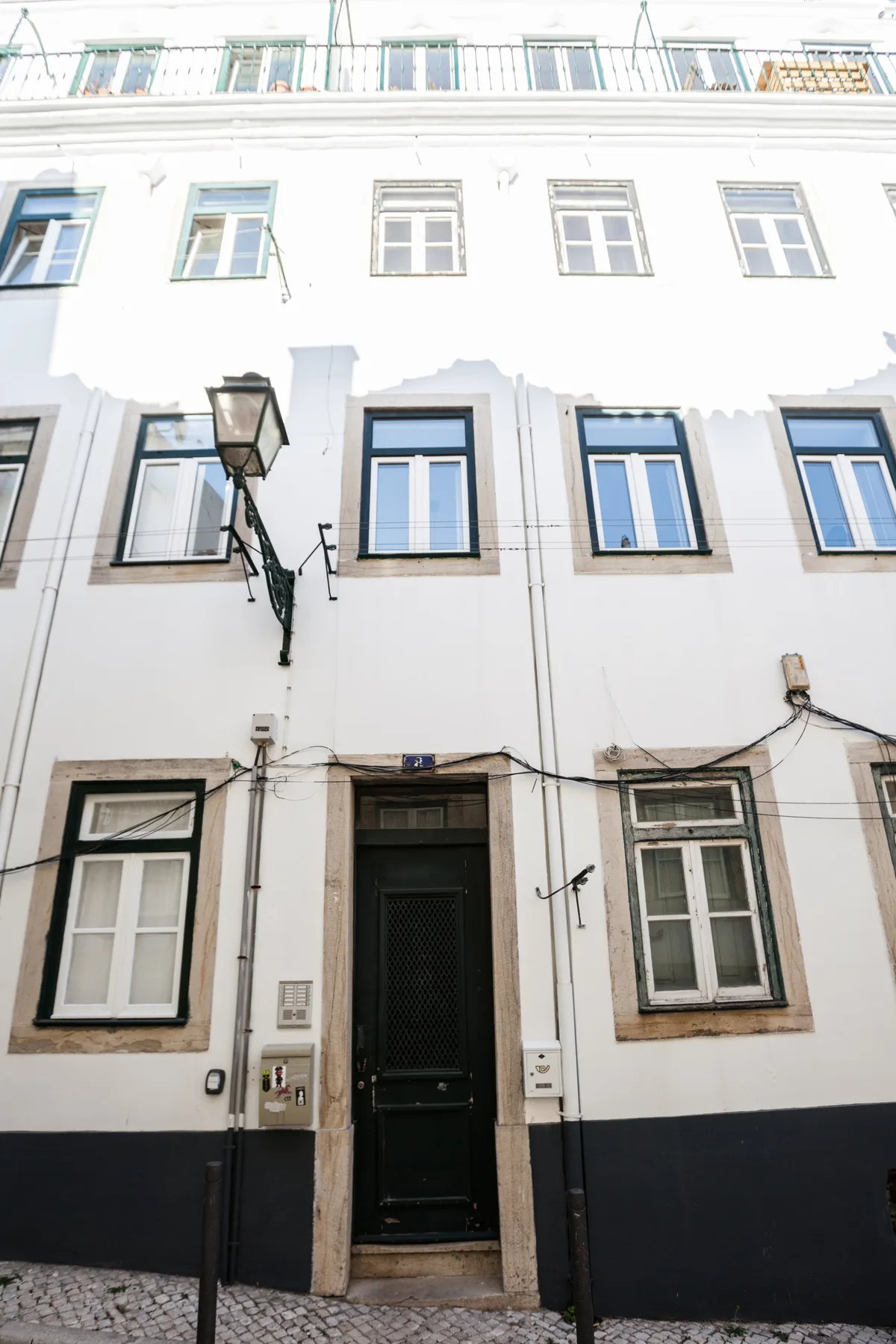 A white multi-story building facade with rows of windows and a dark entrance.