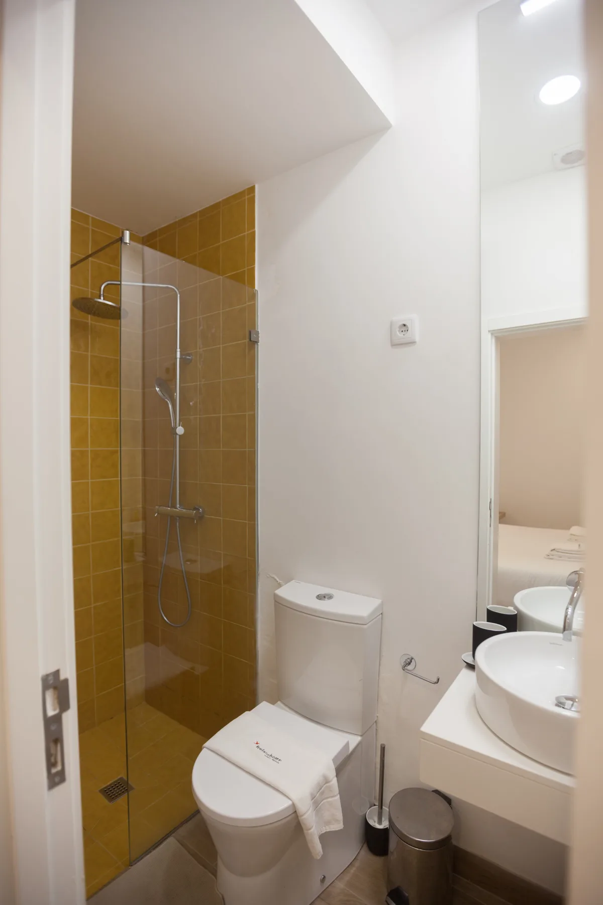 A bathroom with a glass shower, toilet, and sink.