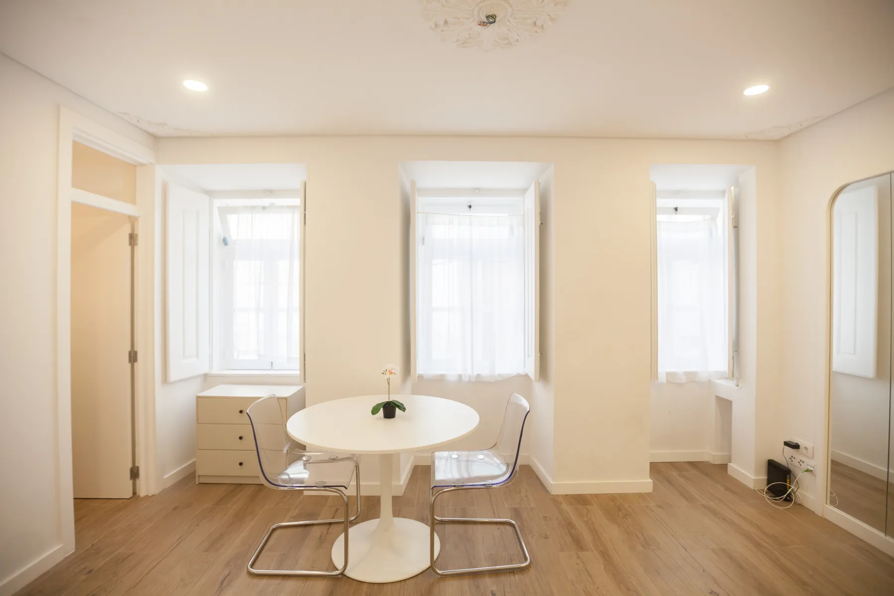 A bright dining area with a round table and tall windows.