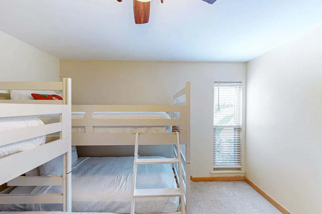 A bedroom with bunk beds and a window with blinds.