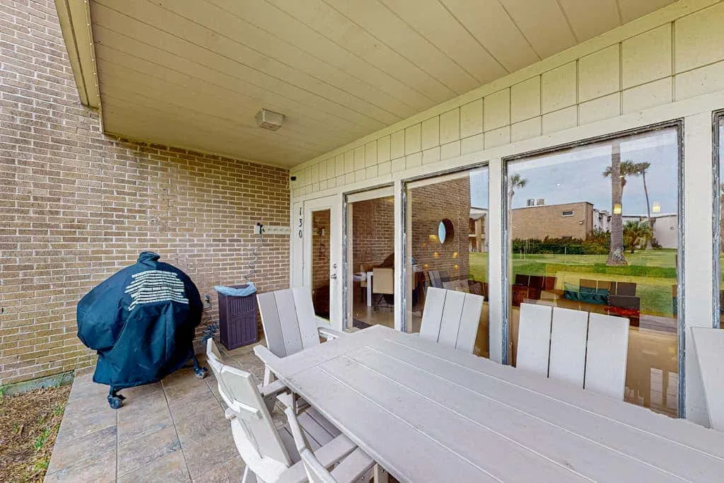 A covered patio with a dining table and sliding glass doors.