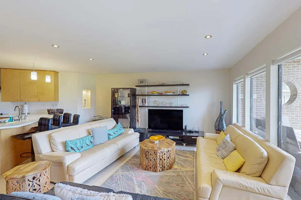 A bright living room with seating, a television, and large windows.
