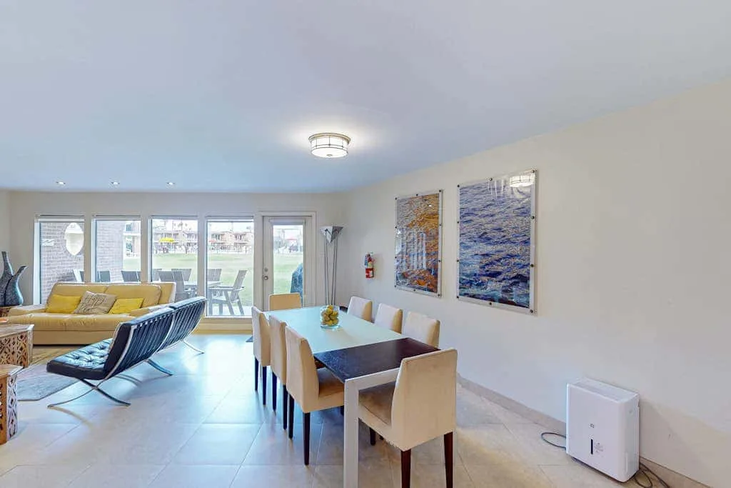 A bright living and dining area with a table, seating, and large windows.
