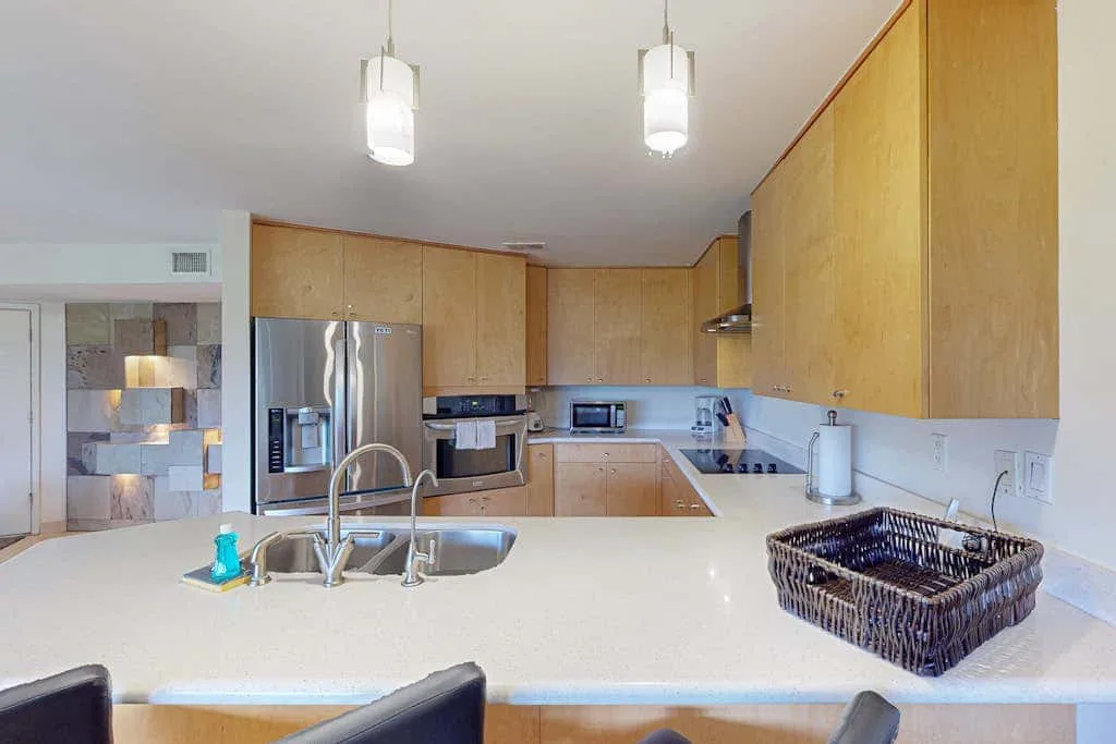 A bright kitchen with wooden cabinets, stainless steel appliances, and a large island.