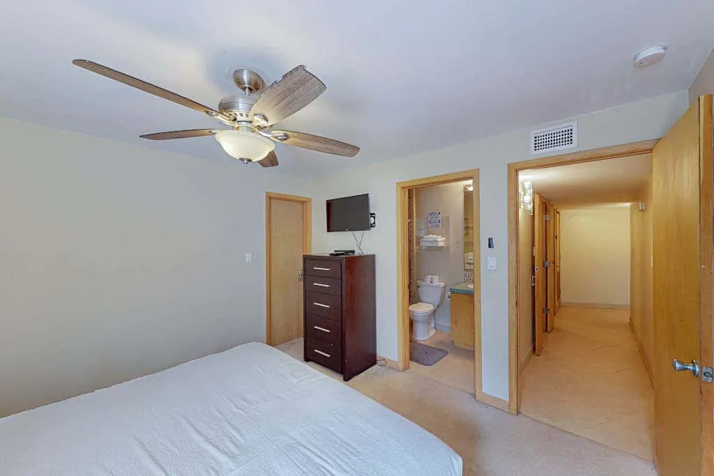 A bedroom with a bed, dresser, and open doorway to a bathroom.