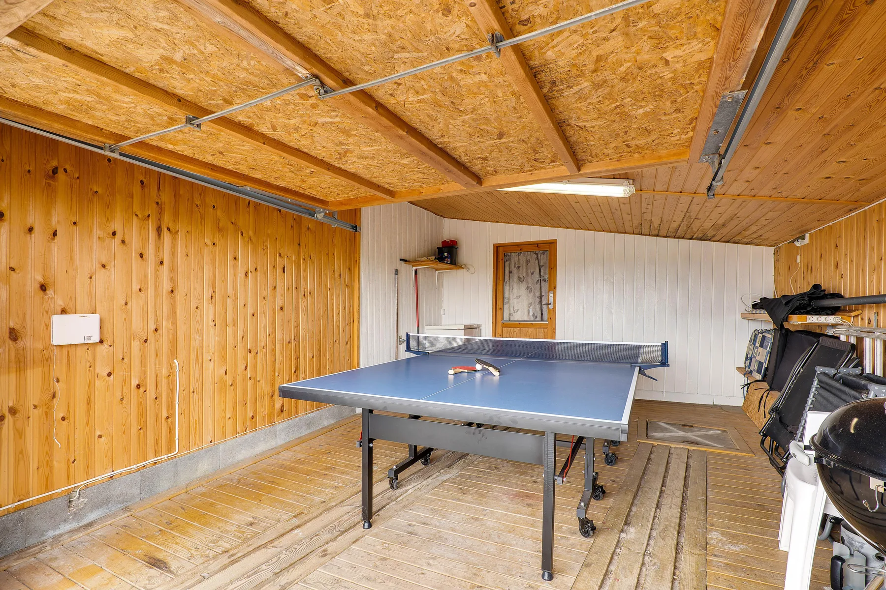Una sala de recreo tiene una mesa de ping-pong y paredes revestidas de madera.
